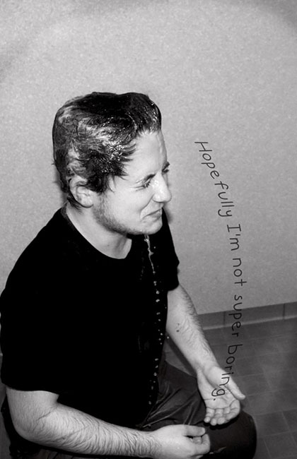 A black and white image of a man shaking water off his face.